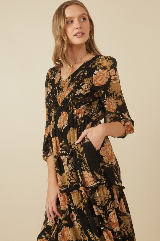 Close up of Hannah floral print smocked dress in black, featuring a V-neckline and tiered skirt.