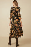Back view of a black floral print smocked dress featuring tiered skirt and three-quarter sleeves.