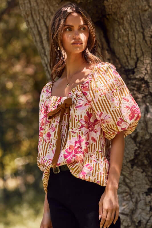 Fuchsia floral and amber striped blouse with puff sleeves and ribbon tie, perfect for a bold, feminine style.