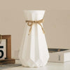 Modern origami vase in white with a decorative bow, perfect for stylish flower arrangements in contemporary interiors.