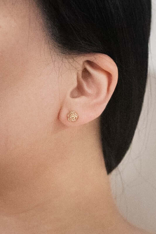 Model wearing Amelia Rose 14K gold-plated stainless-steel stud earrings featuring a delicate flower design.