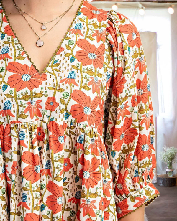 Close-up of In the Meadow Floral Mini Dress in Coral and Cream, featuring a V-neck and puff sleeves, perfect for warm days.