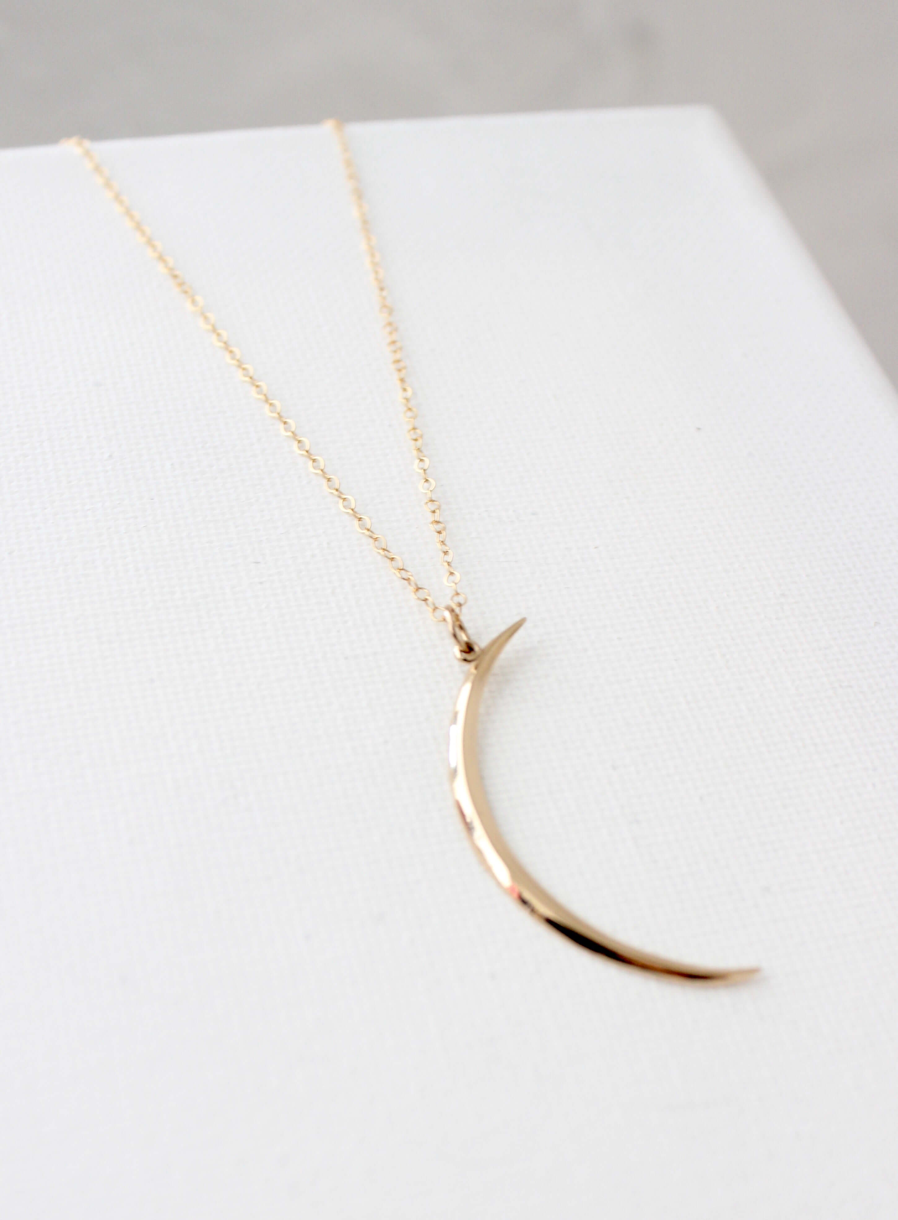Gold crescent moon necklace on an 18