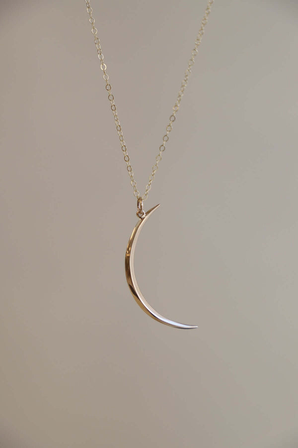 Gold crescent moon necklace on an 18" chain, perfect for layering or gifting to moon and star lovers.