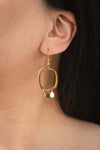 Model wearing Elegant 14K gold-plated earrings with rounded rectangles and teardrop charms.