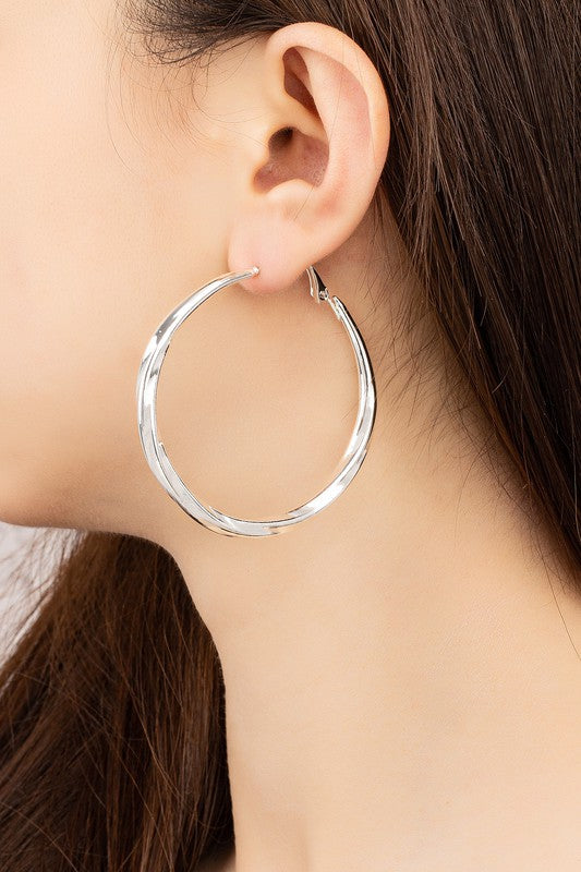 Silver twisted tube hoop earrings worn on a model, showcasing their modern design and elegance.