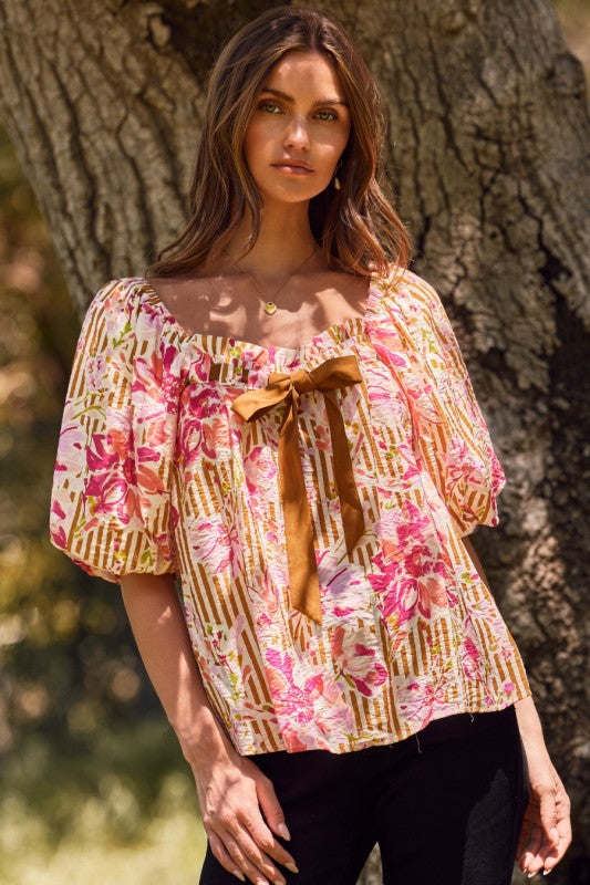 Fuchsia floral and amber striped blouse with puff sleeves and ribbon tie, perfect for a feminine wardrobe upgrade.