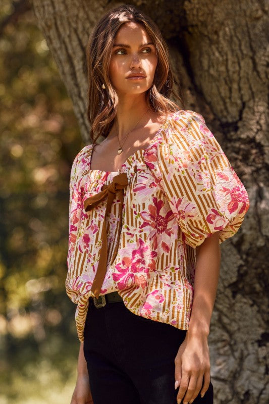 Fuchsia floral and amber striped blouse with puff sleeves and ribbon tie, perfect for a bold, feminine style.